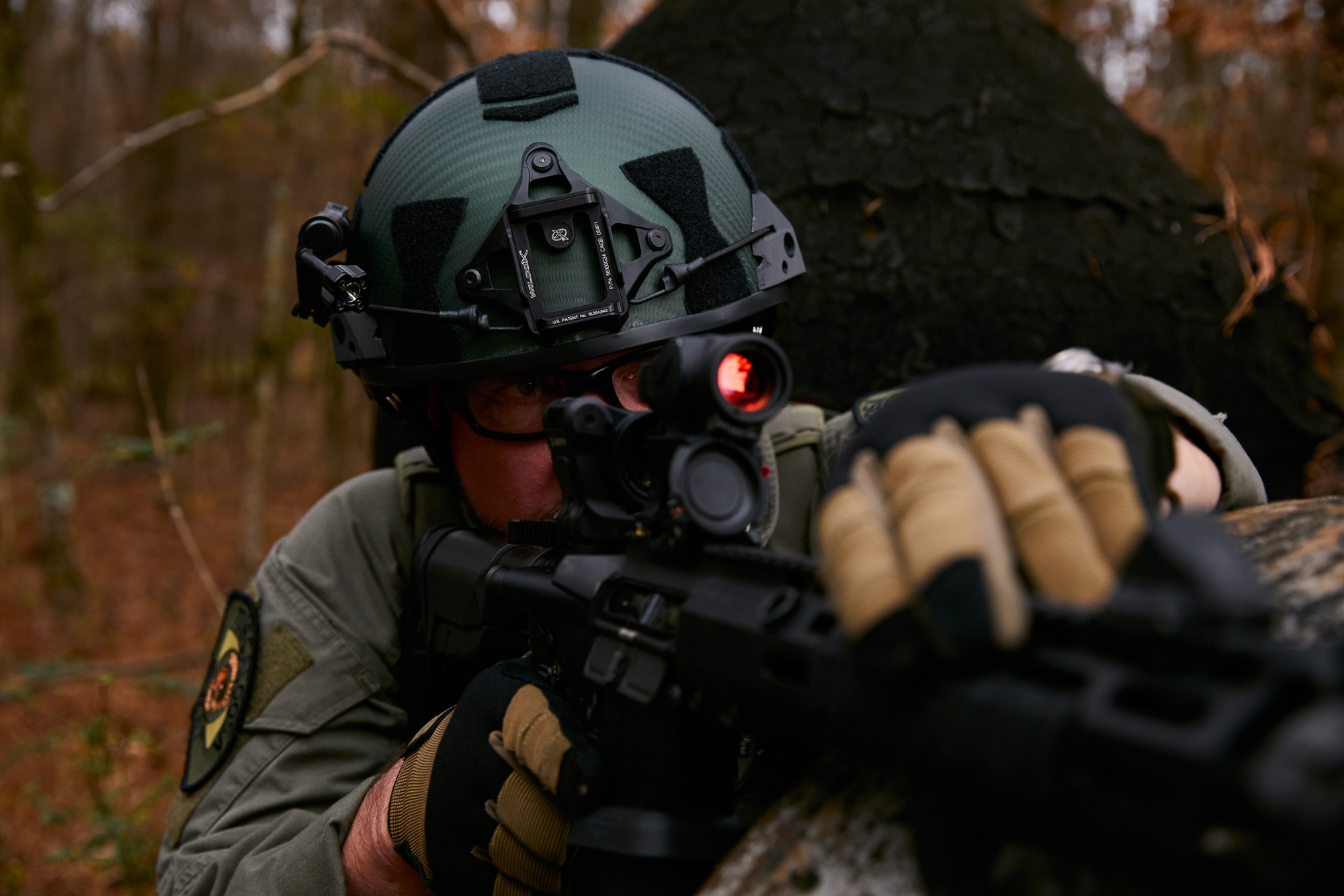 Tactical operator in a wooded training environment wearing a ballistic helmet